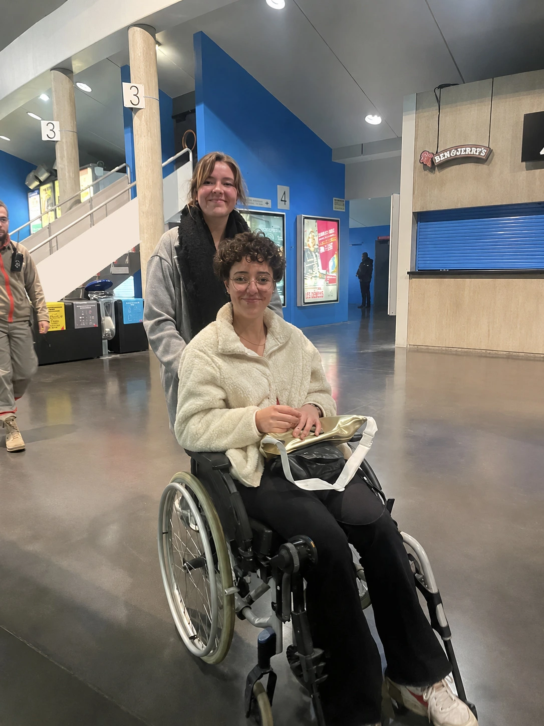 Two friends enjoying a cinema outing together, one using a wheelchair