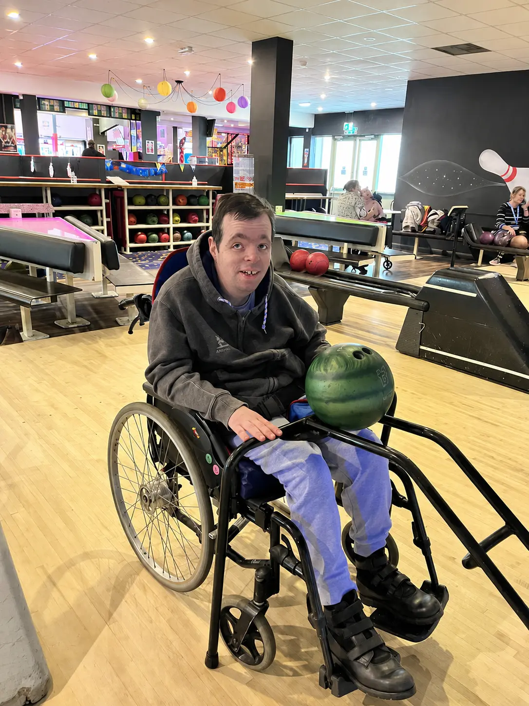 Client holding a green bowling ball at the lanes